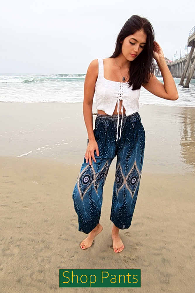 Model wearing the 'Paris Pants' blue elastic top pants, which features a bohemian print and a flowing silhouette. The image includes a 'Shop Now' button.