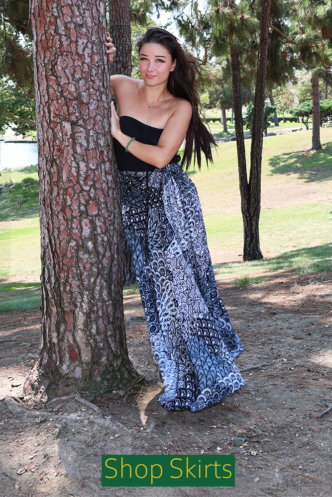 Model wearing the 'Maui Skirt' blue elastic top midi skirt, which features a bohemian print and a flowing silhouette. The image includes a 'Shop Now' button.